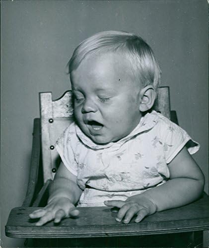 תצלום וינטג 'של תינוק מתנדנד ויושב על כסא גבוה.